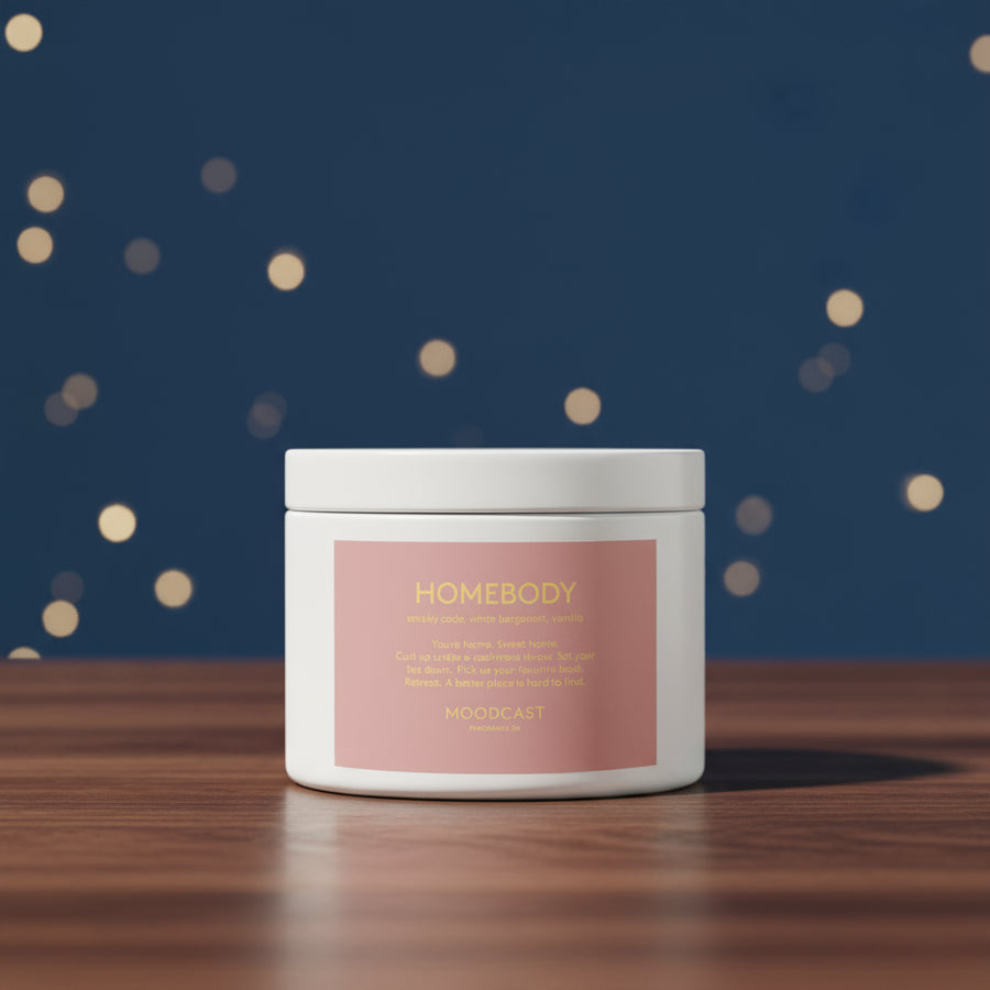 A white travel tin candle with a blue label that reads 'DAYDREAMER' from the brand MOODCAST., styled