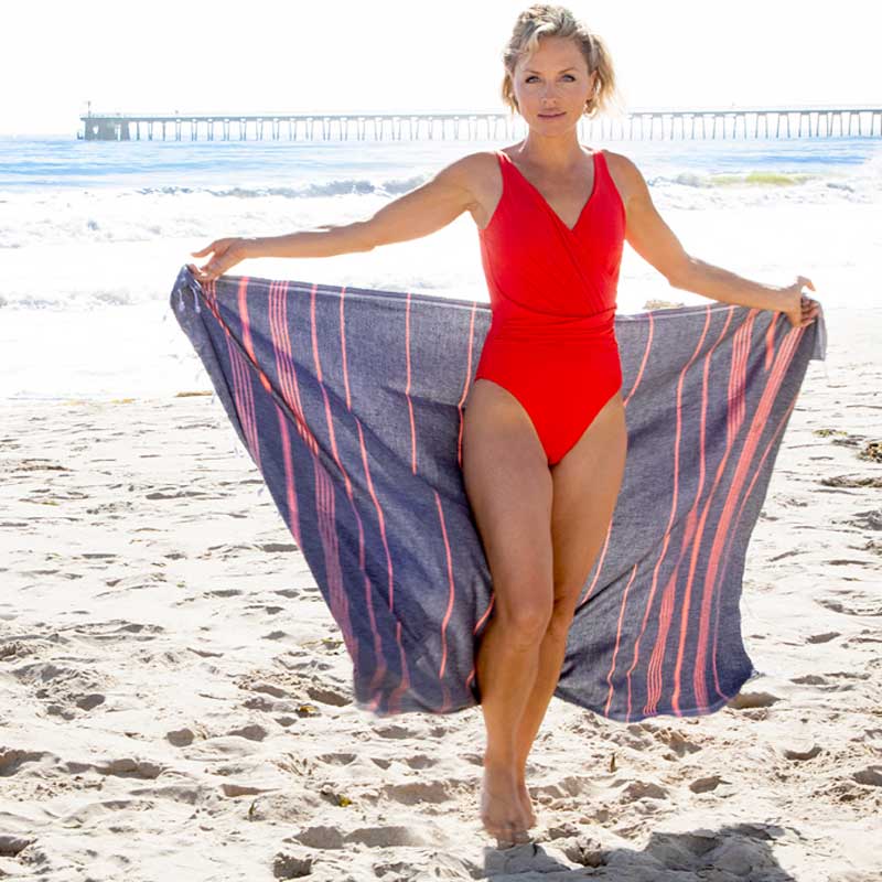 Pink Turkish towel used on a sandy beach, lightweight and quick-drying