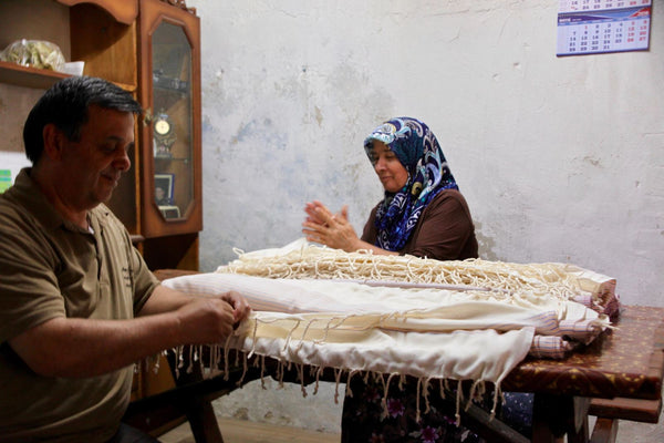 Artisan hand-knotting the fringe on a Turkish towel at a village workshop