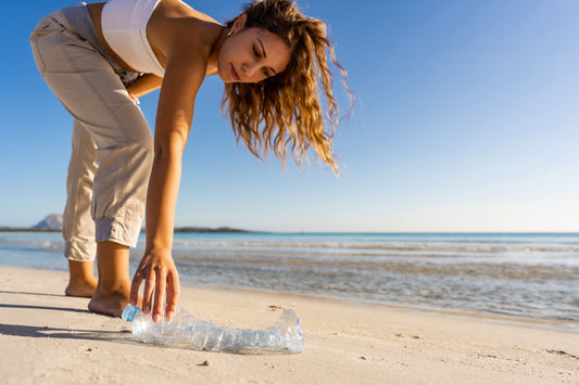 Woman picking up a plastic bottle on the beach