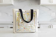 Tote bag with colorful illustration of Santa Barbara on a wooden surface