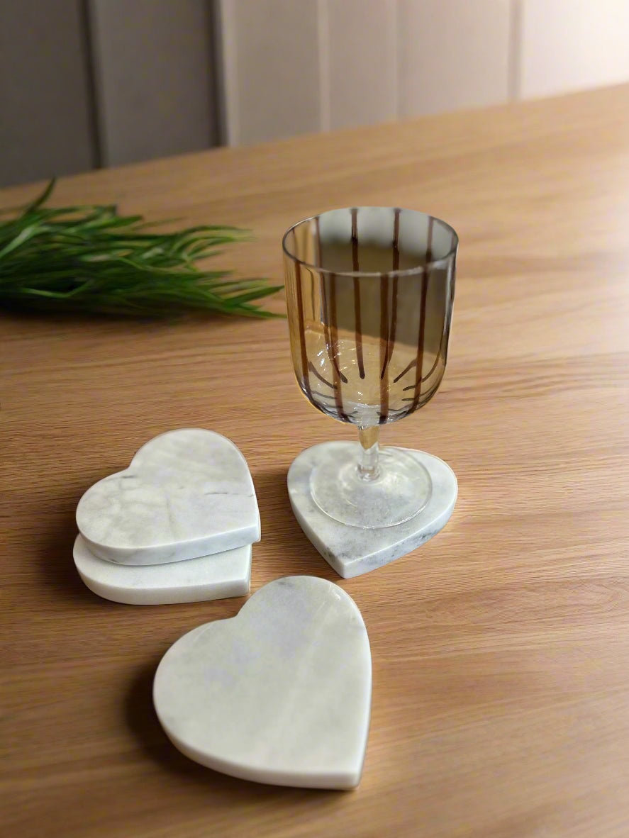 Heart-shaped coasters on a wooden surface with a glass of wine.