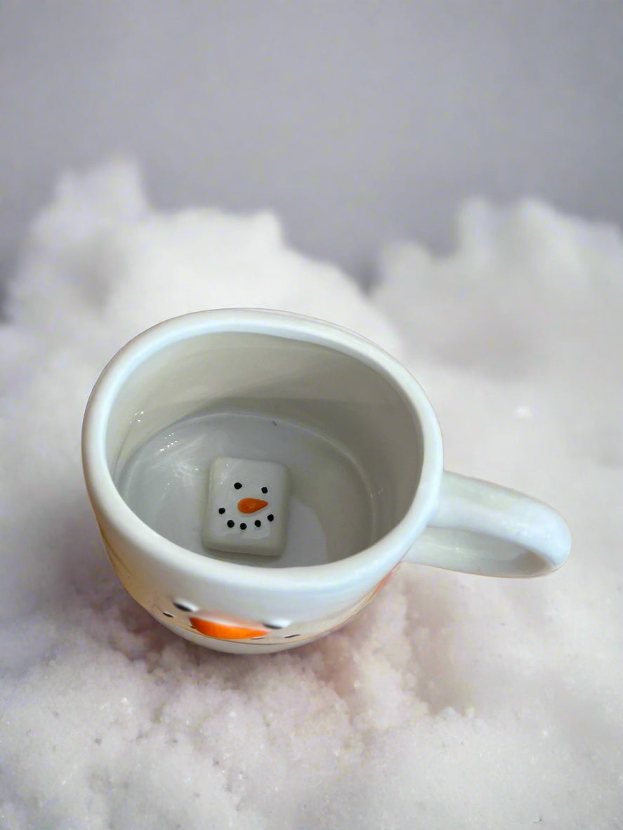 Ceramic mug with a snowman design on a snowy background