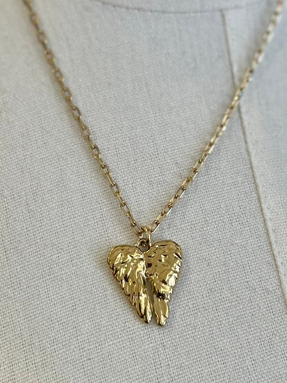 Gold heart-shaped pendant necklace on a light gray background
