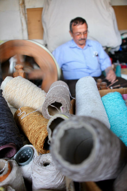 Spools of cotton yarn beside a hand-weaving station