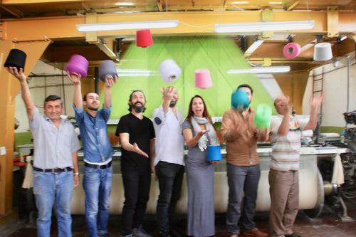 The weaving team holding bobbins of cotton yarn in front of the loom